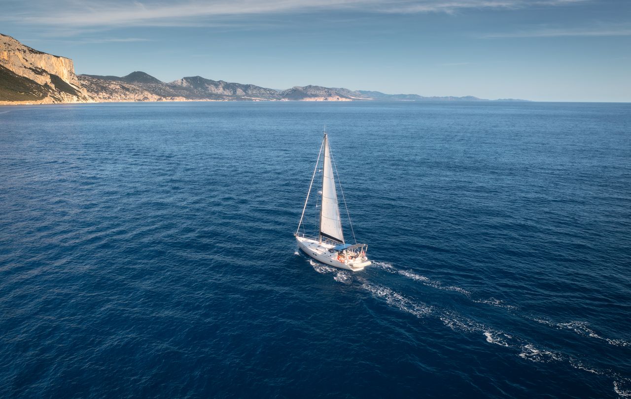 Voilier au près le long d'une côte rocheuse